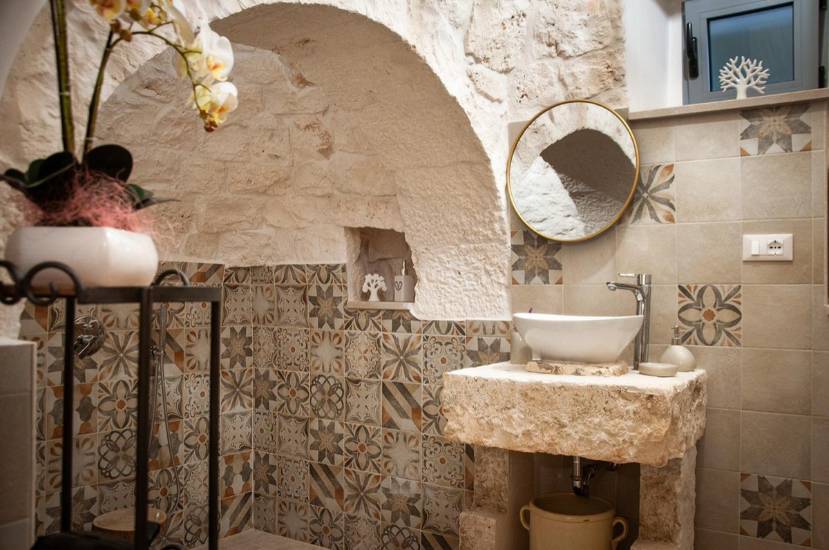 Il bagno: il lavabo su un blocco di pietra e, sotto l’arco del cono, la doccia