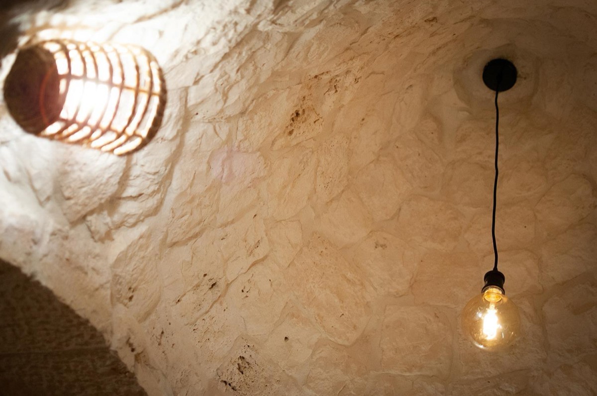 L’interno di un cono visto da sotto: la pietra chiara sale verso il centro, da cui pende una lampadina