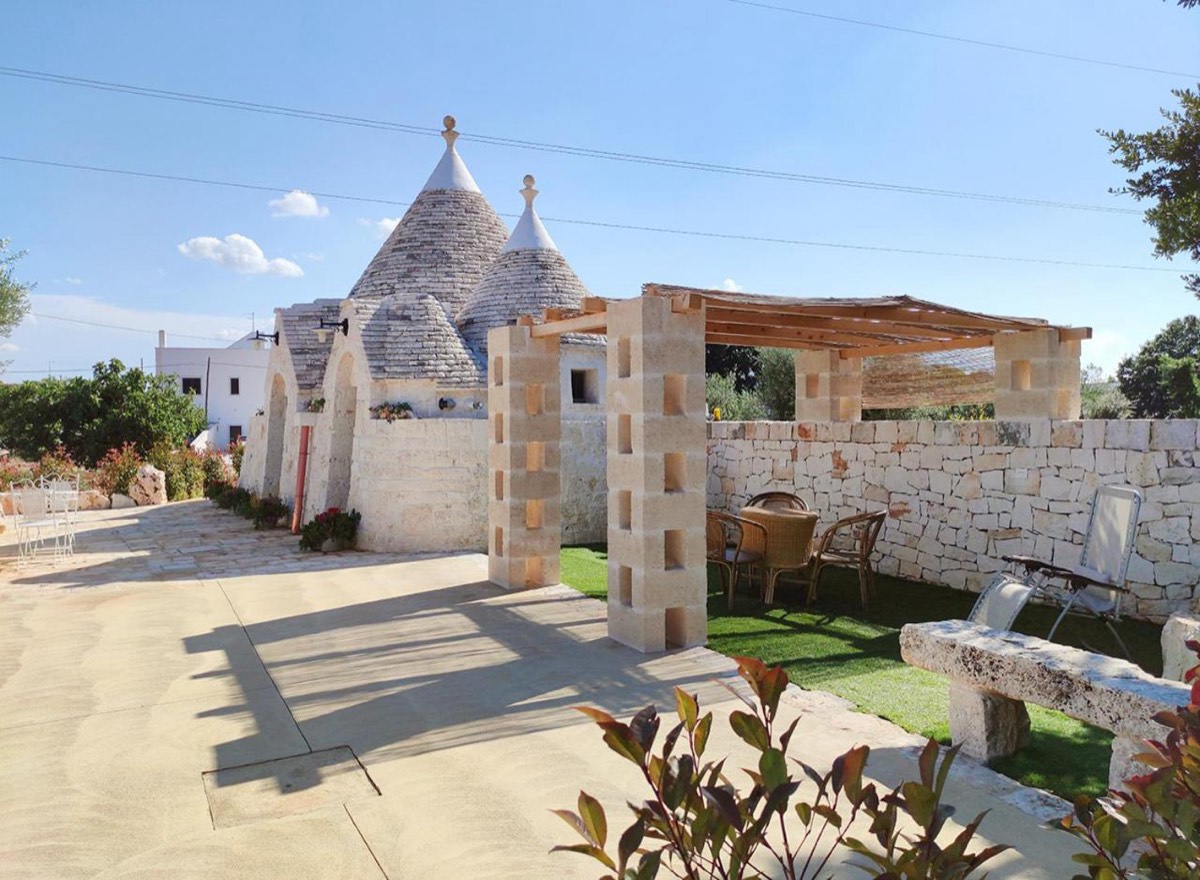 Il pergolato con il tavolo e le sedie, accanto ai coni del trullo